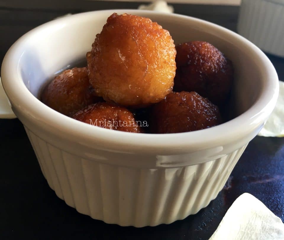 A bowl of food on a plate, with Sweet potato and Gulab jamun