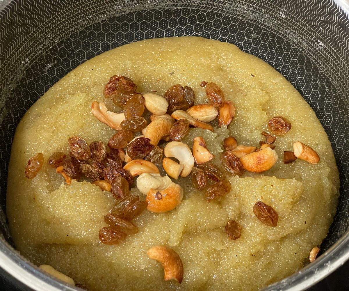 A pan is with vegan rava kesari and topped with nuts and raisins.