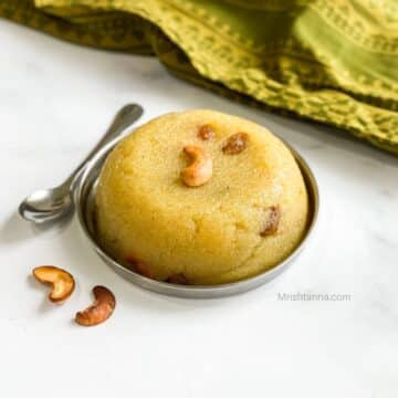 A plate of vegan rava kesari is topped with nuts.