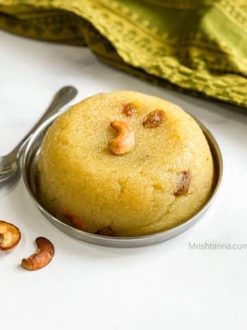 A plate of vegan rava kesari is topped with nuts.