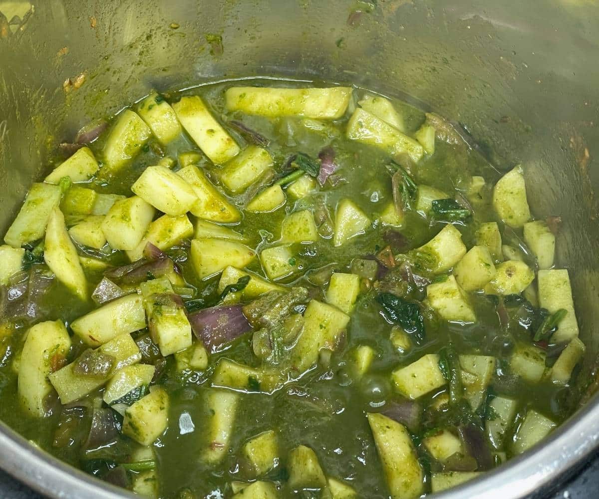 A pot is with aloo palak on cooking mode.