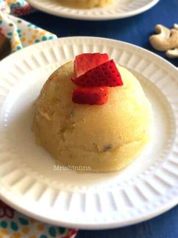 A plate is with vegan rava kesari and topped with strawberries.