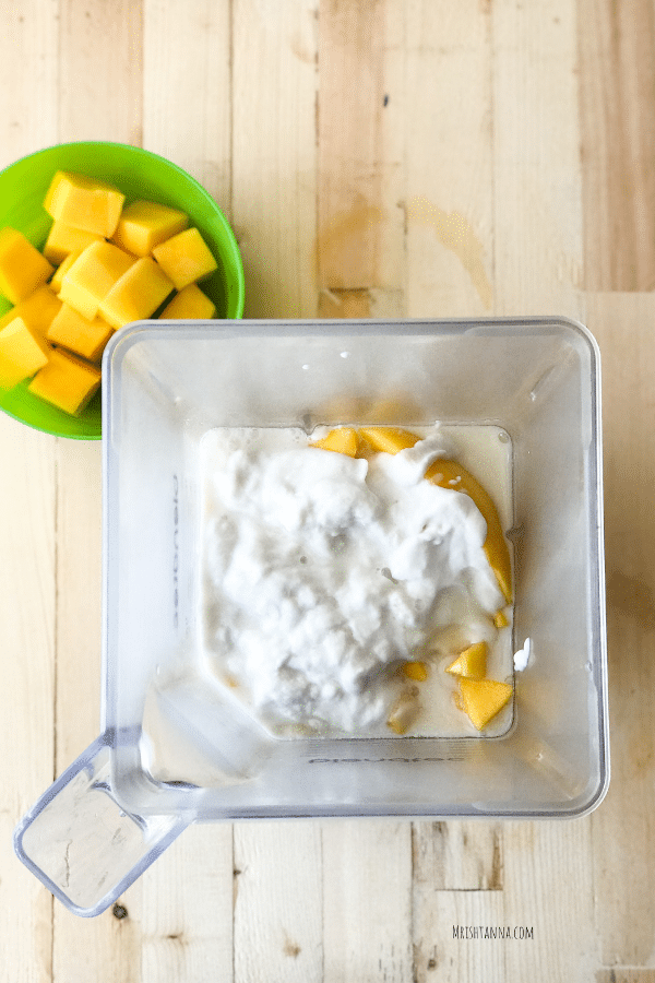 A blender is filled with, Mango, yogurt and milk for lassi