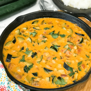 A pan of zucchini curry on a table and topped with cilantro