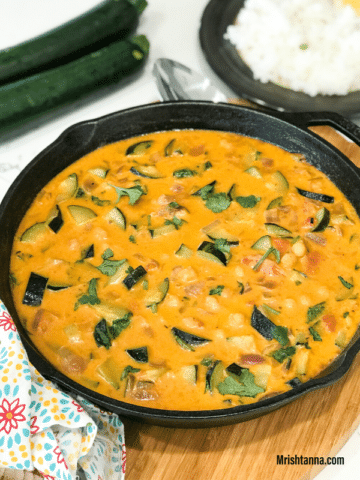 A pan of zucchini curry on a table and topped with cilantro