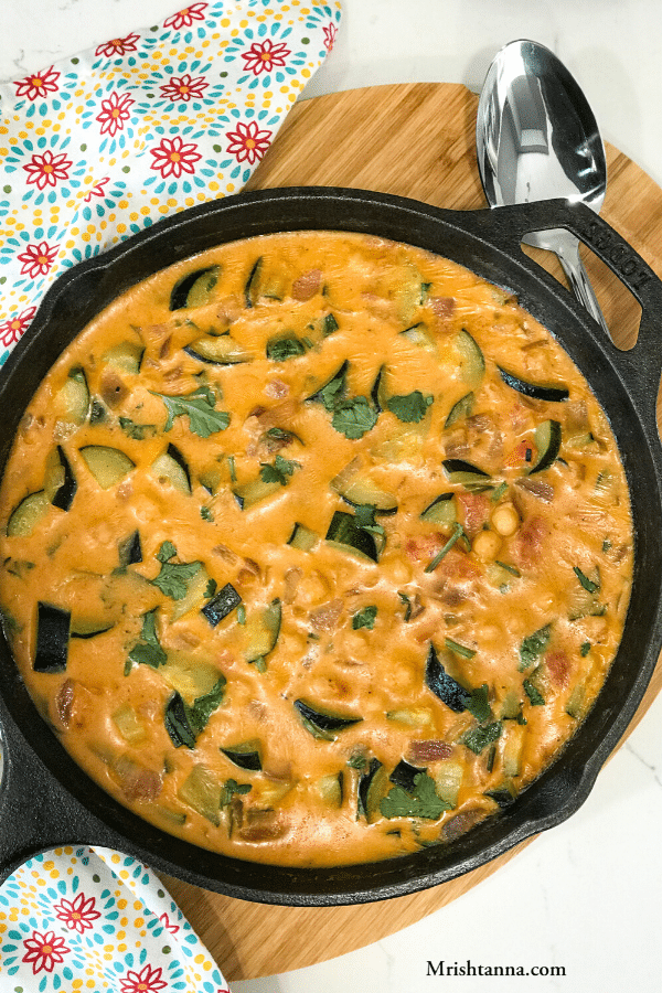 A cast iron pan with Zucchini Curry and placed on the table