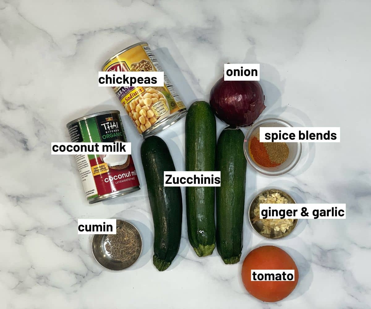 All the ingredients for zucchini curry are placed on the white marble table.