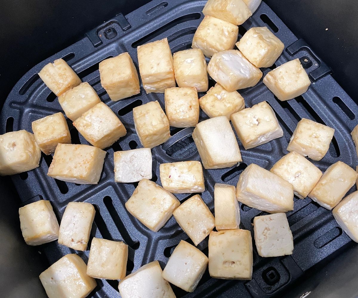 Air fryer basket is with fried tofu.