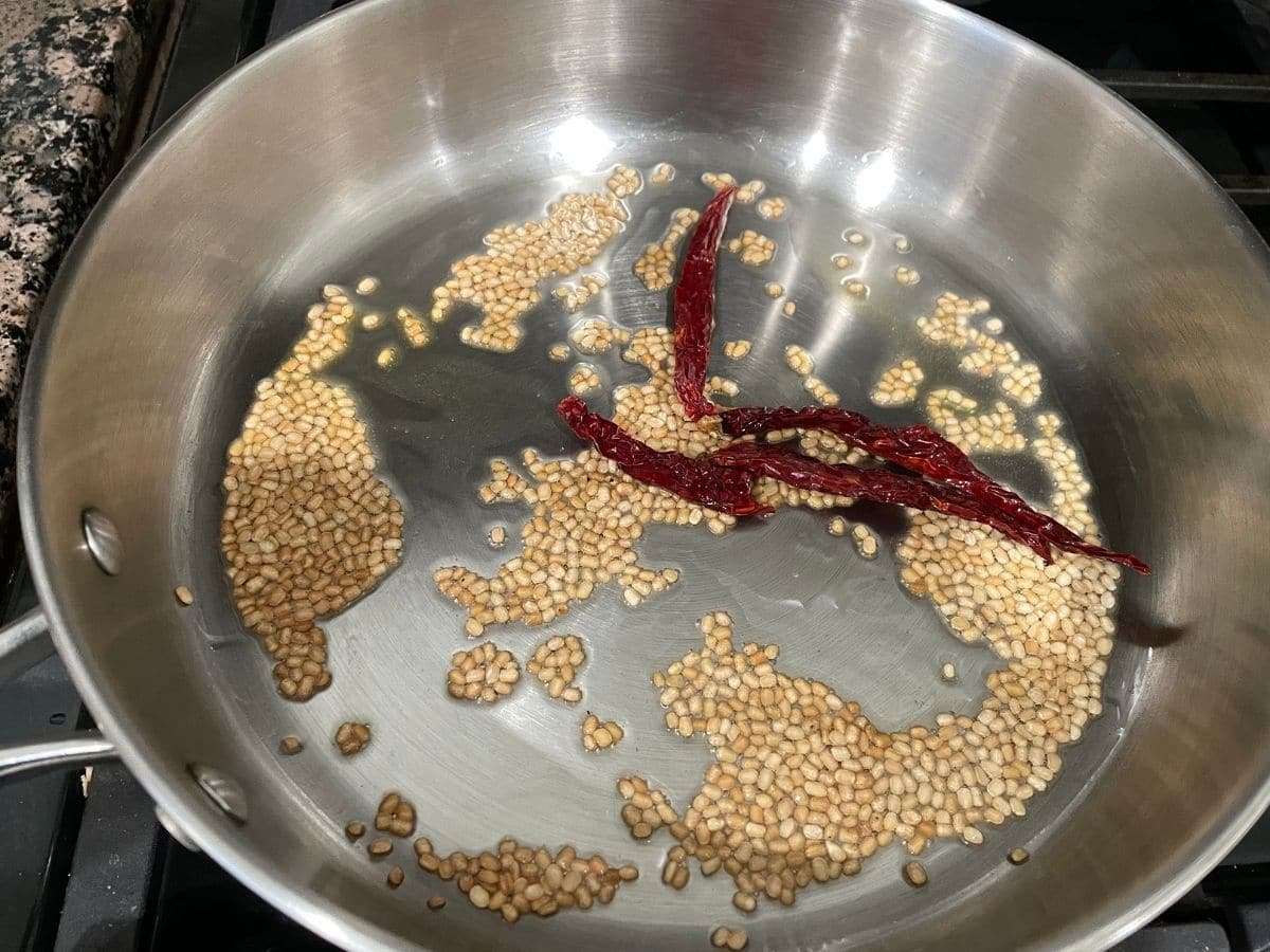 A pan is with oil, urad dal and red chilies over the heat.