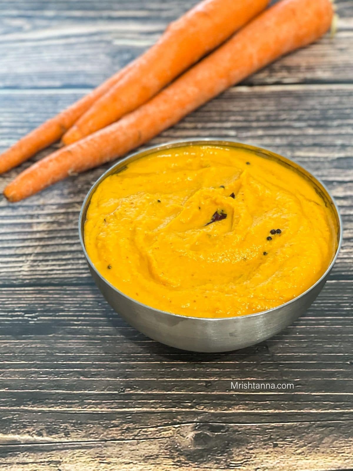 A steel bowl is filled with carrot chutney.