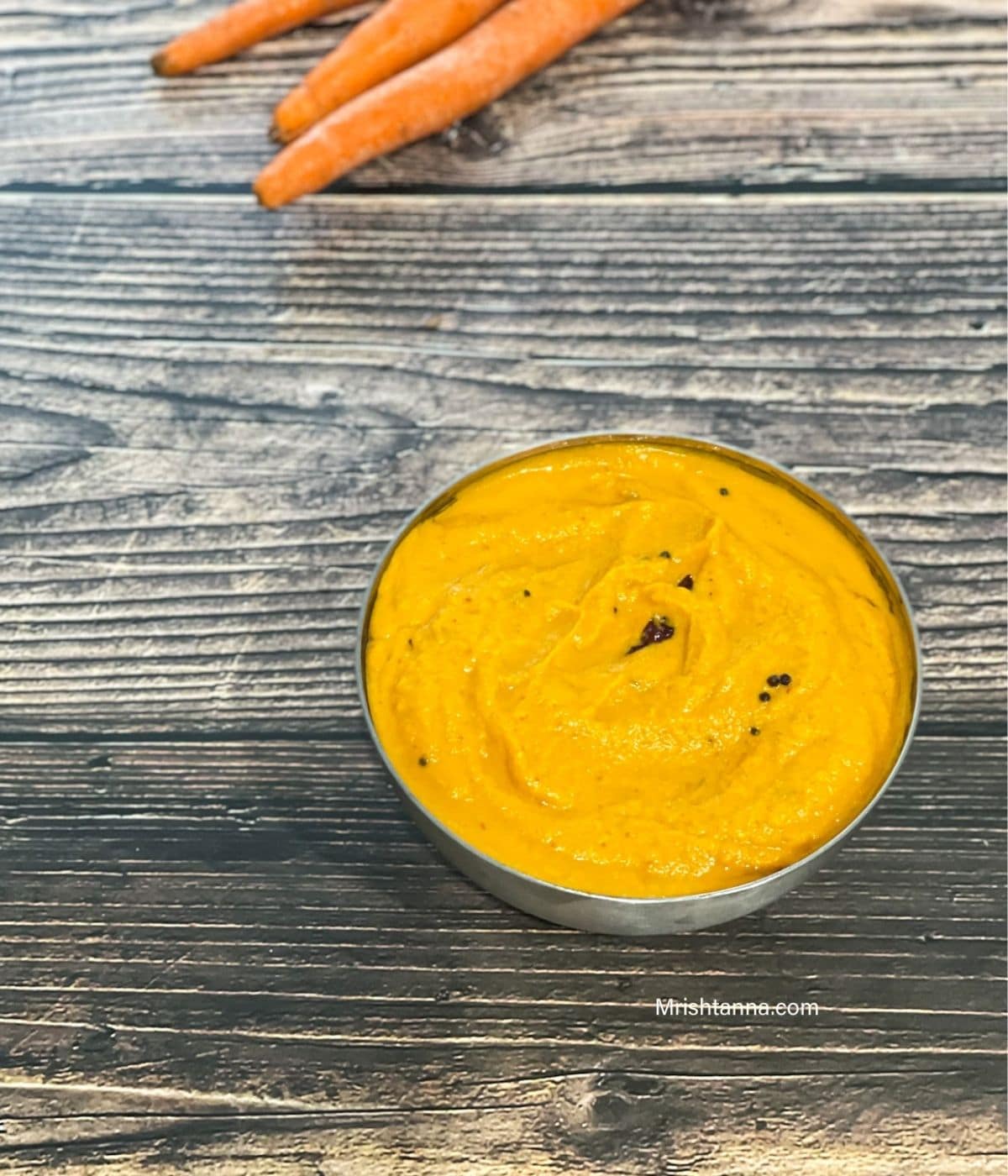 A steel bowl of carrot chutney is on the table