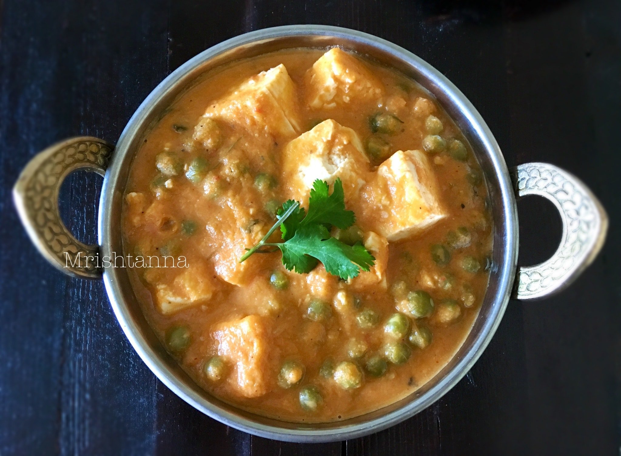 A close up of a bowl curry, with Tofu and Peas