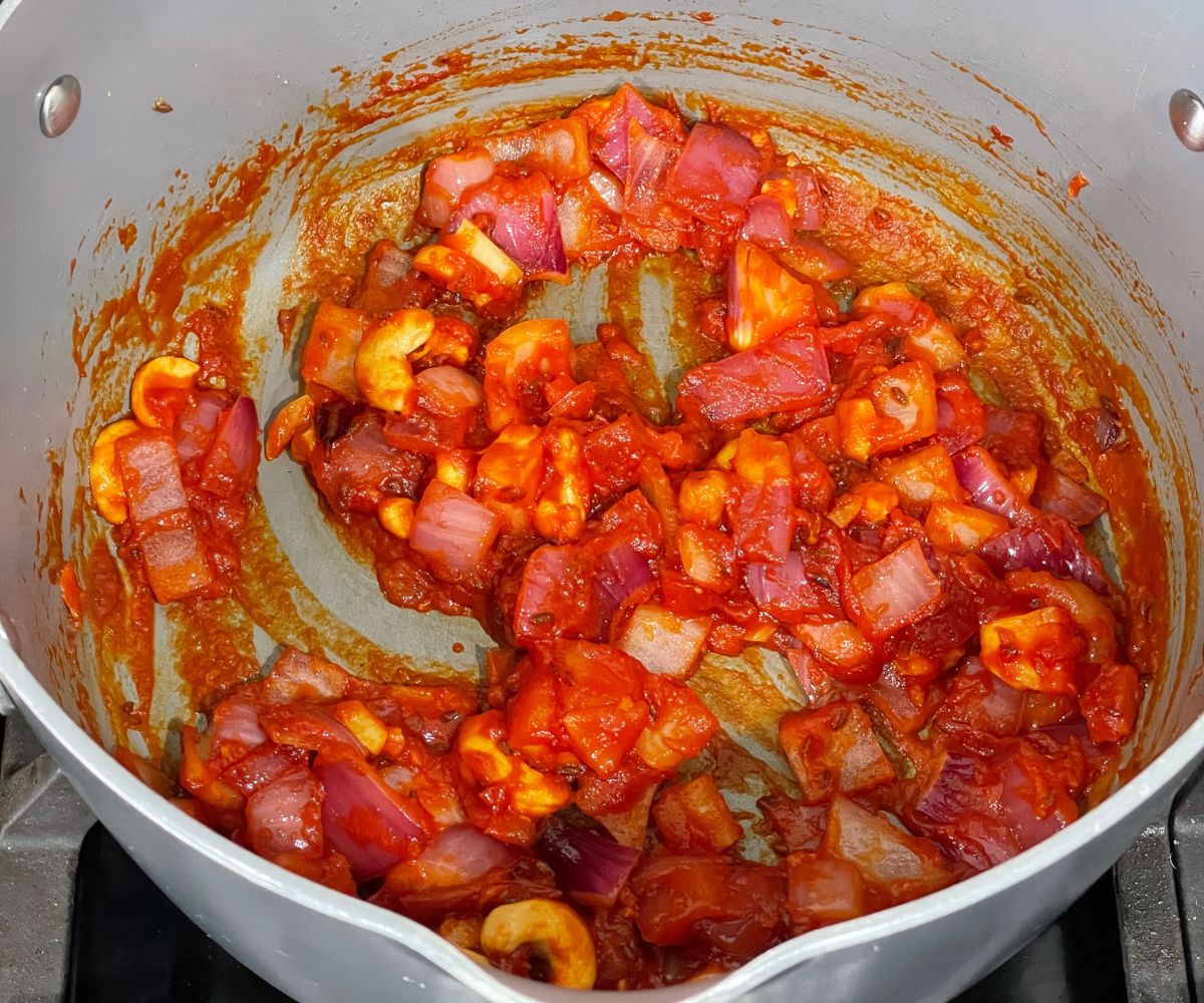 A pan is with tofu matar masala over the flame.