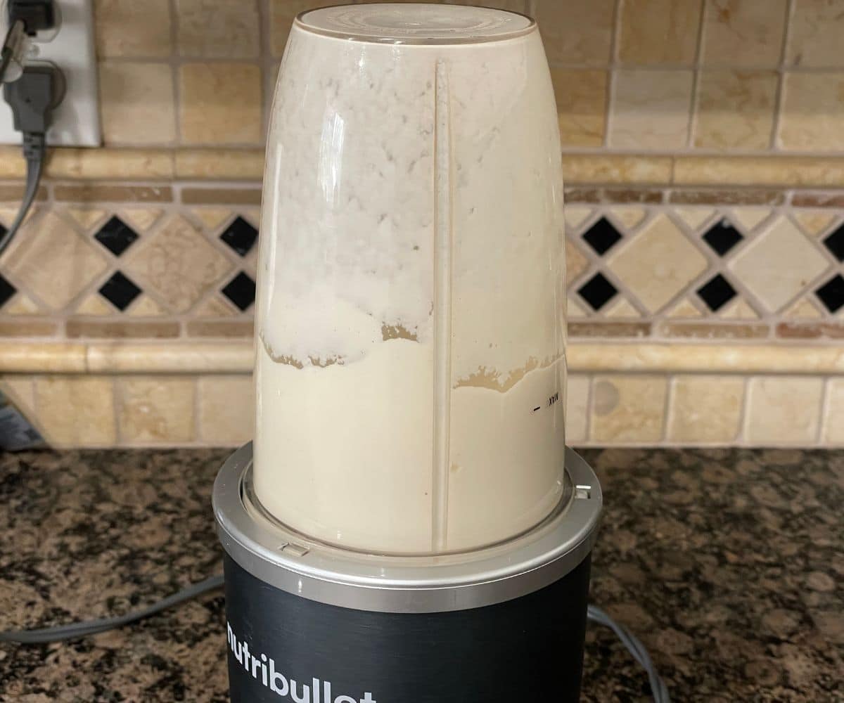 Cashews and oat milk being blended together.