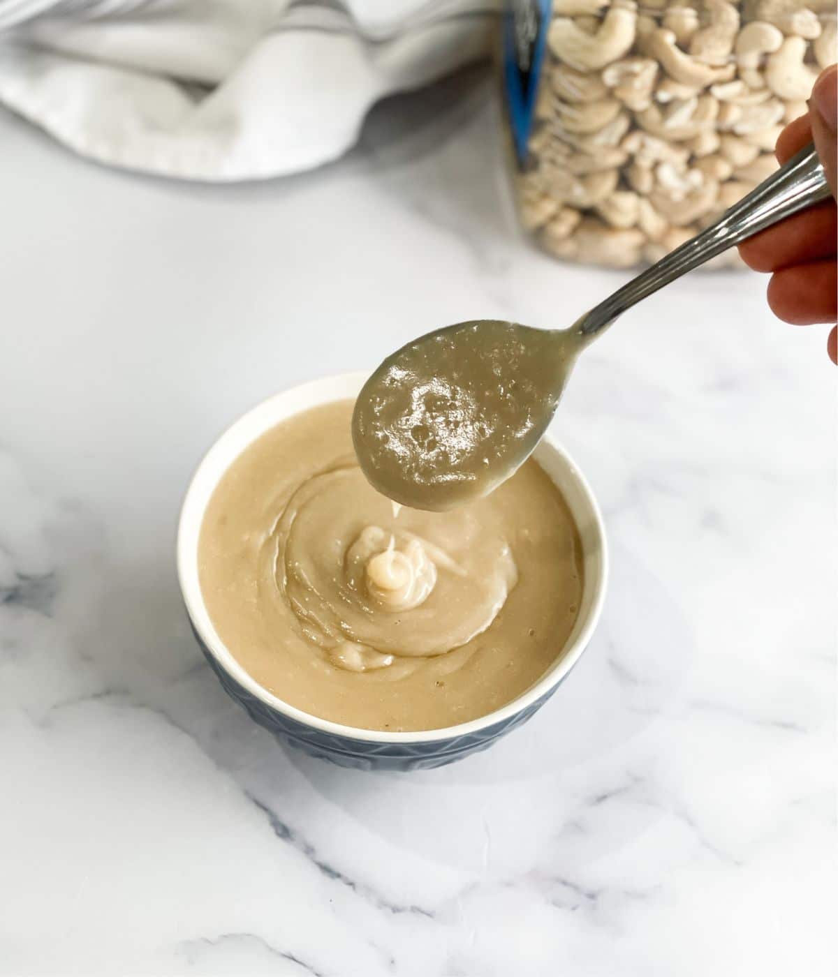 A person is holding a spoon of vegan condensed milk.