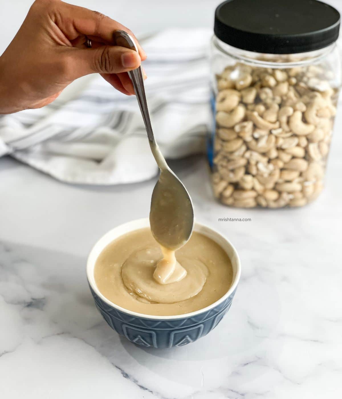 A person is lifting a spoon of vegan condensed milk.