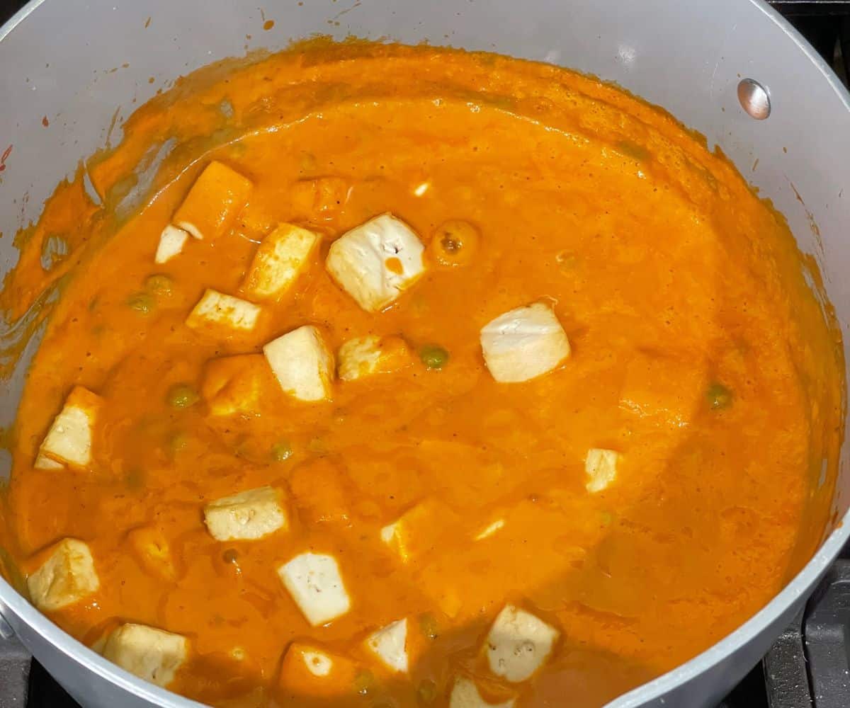 A pot is filled with vegan matar paneer masala over the heat.