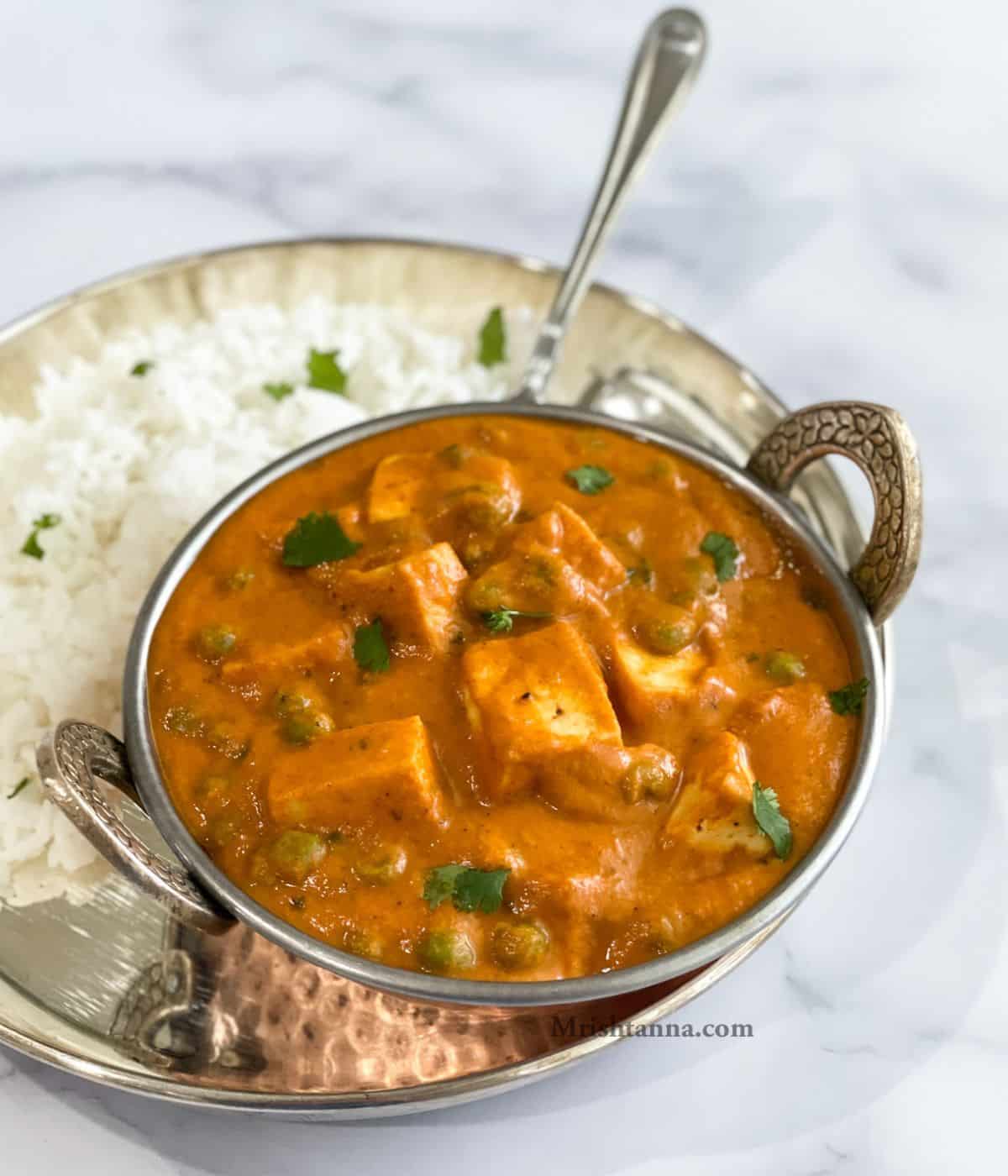 A bowl of vegan matar paneer and rice on the table.