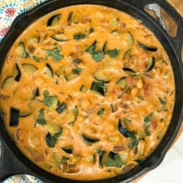 A pan of zucchini curry on a table and topped with cilantro.