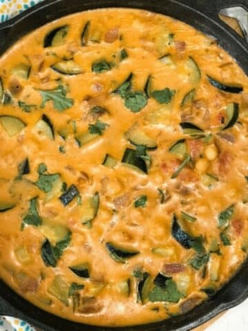 A pan of zucchini curry on a table and topped with cilantro.