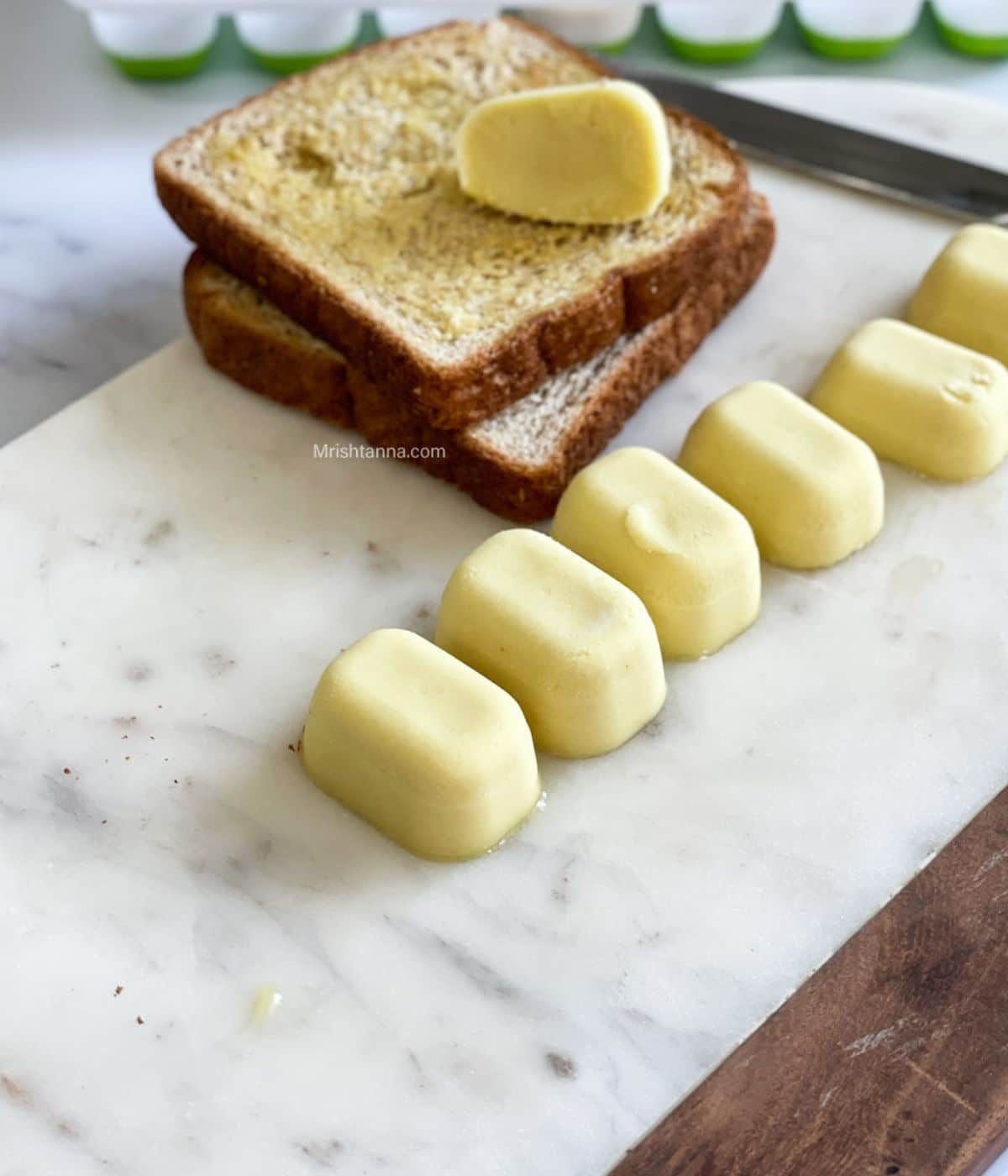 vegan butter cubes are on the white marble tray with toasted bread on the side.