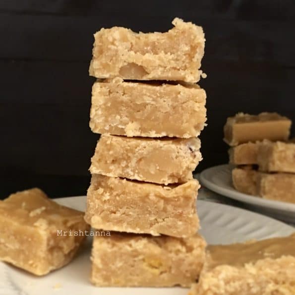 A half-eaten burfi on a plate, with  Gram flour