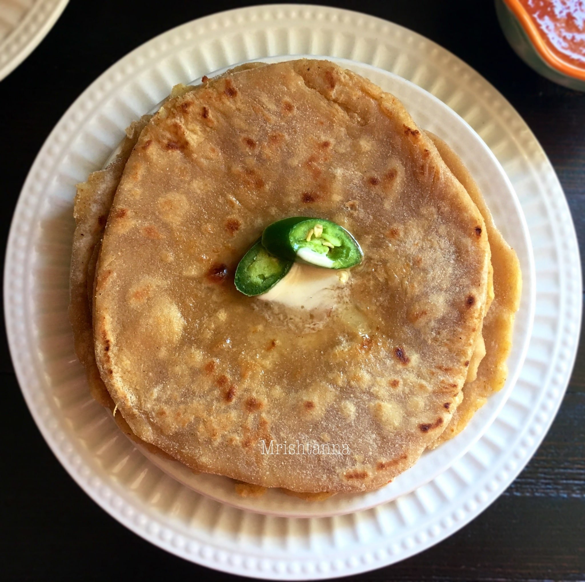Paratha is stacked on the white serving plate