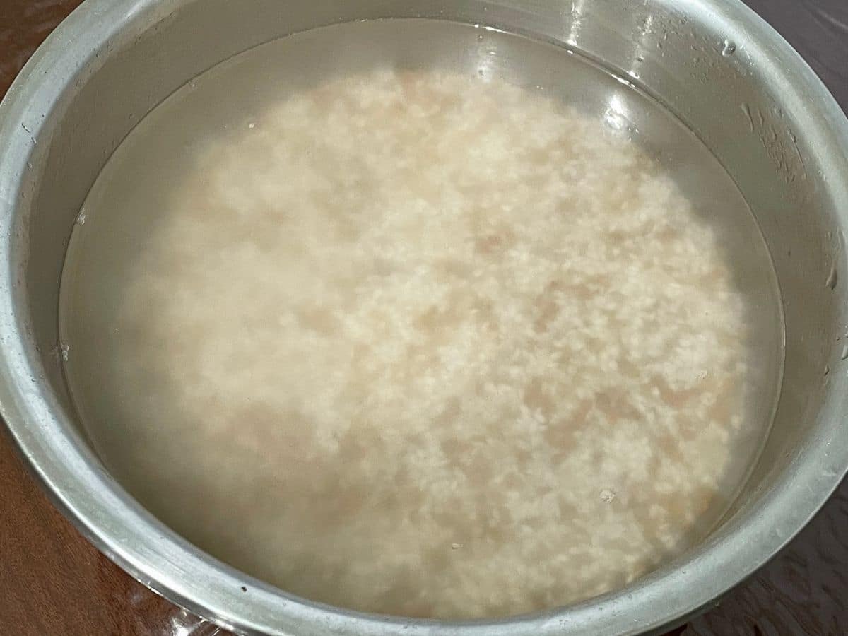 A bowl is with soaked rice and methi seeds