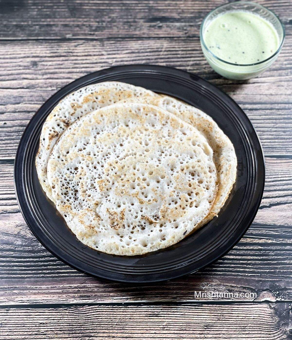 A plate of methi dosa along with chutney in the bowl is on the table