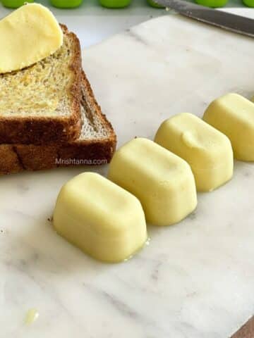 A tray is with vegan butter cubes and toasted bread by the side.