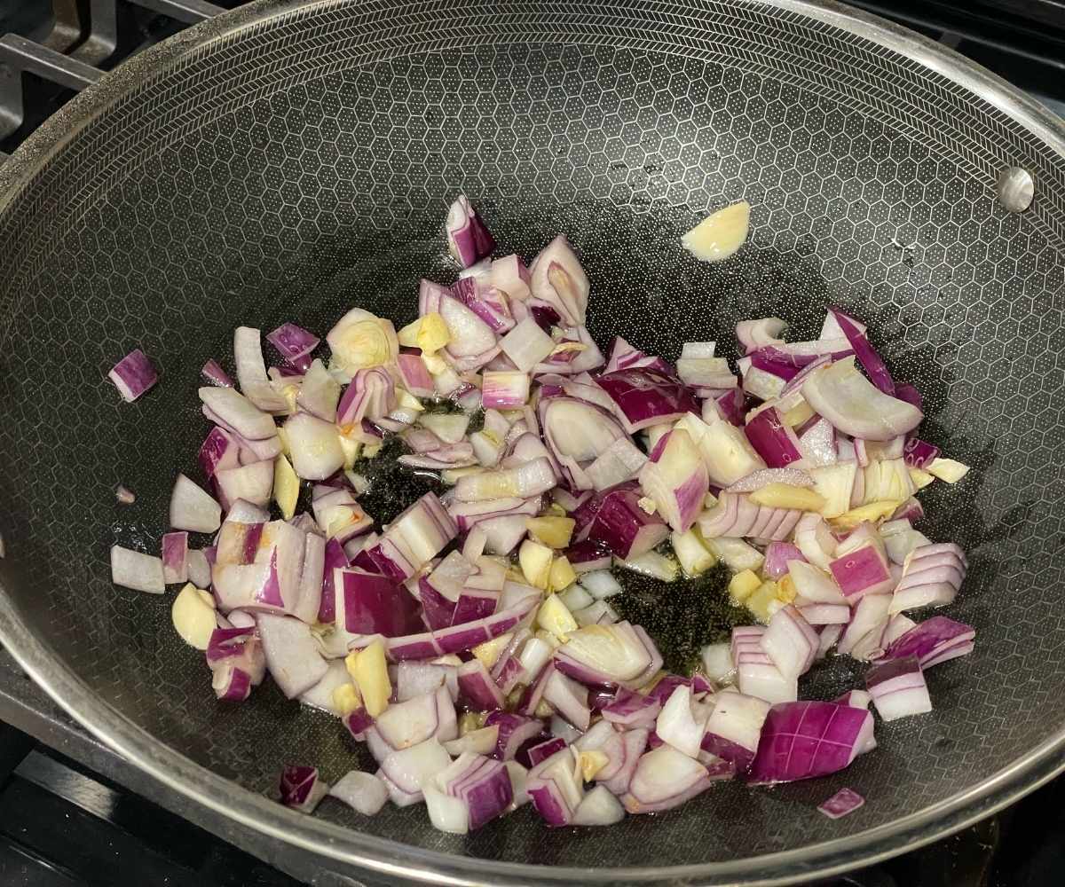 A saucepan is with onions, garlic and ginger over the heat.