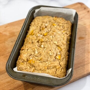 A loaf pan is with baked mango bread.