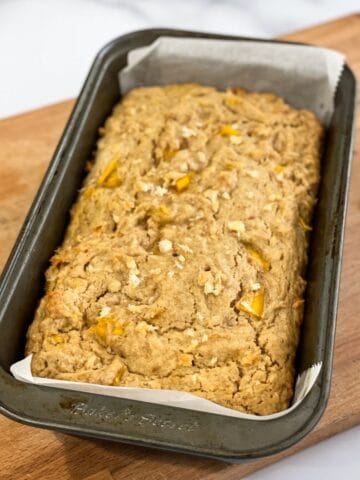 A loaf pan is with baked mango bread.