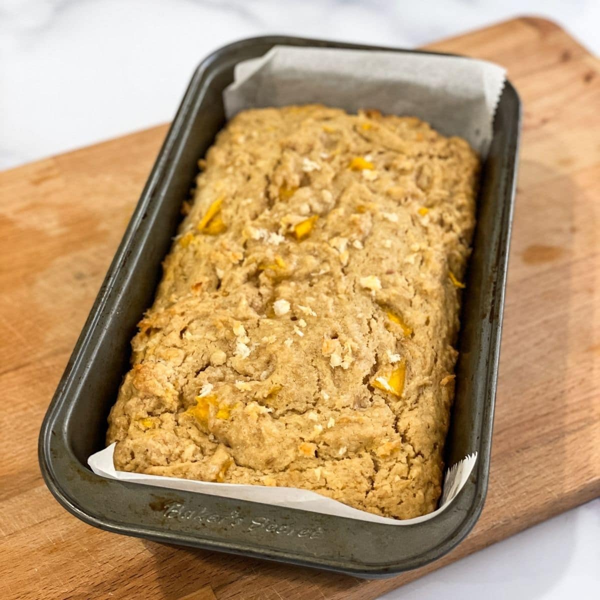 A loaf pan is with baked mango bread.