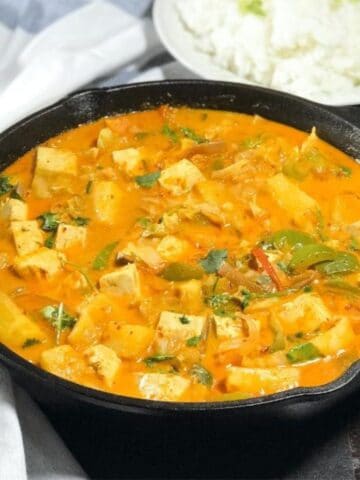 A cast-iron pan is filled with pineapple curry and topped with chopped cilantro