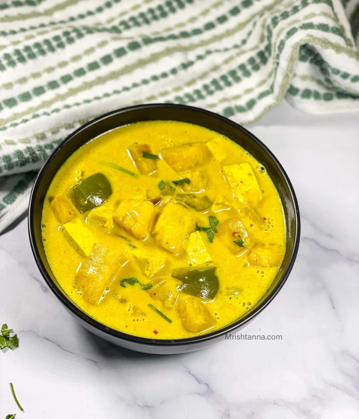 A bowl of pineapple curry is on the marble table.