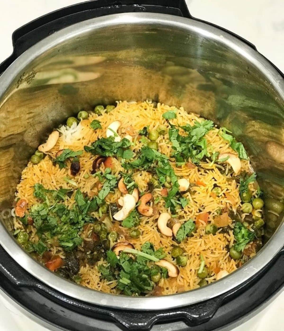 An instant pot is with mint rice and topped with nuts and cilantro.
