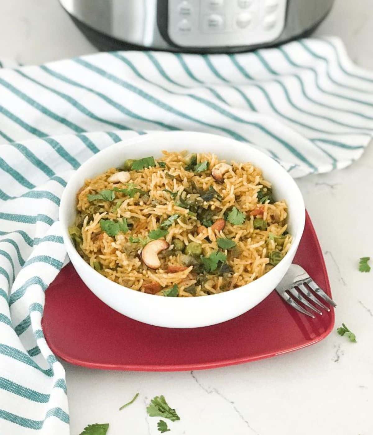 A bowl of pudina pulao is on the plate with a fork.