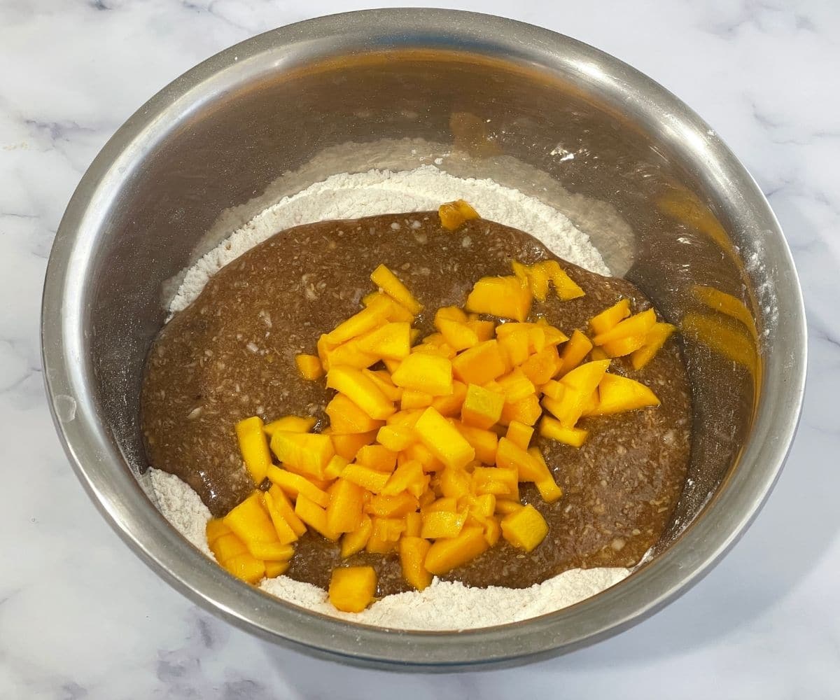 A large mixing bowl is with mango bread mixtures.