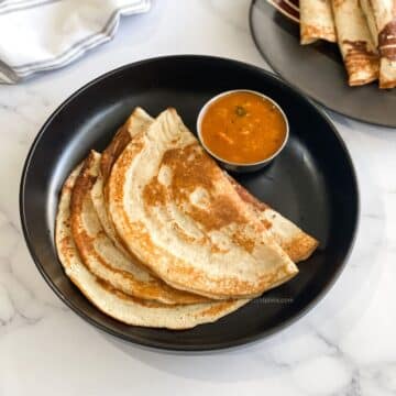 A plate has quinoa dosas with sambar.