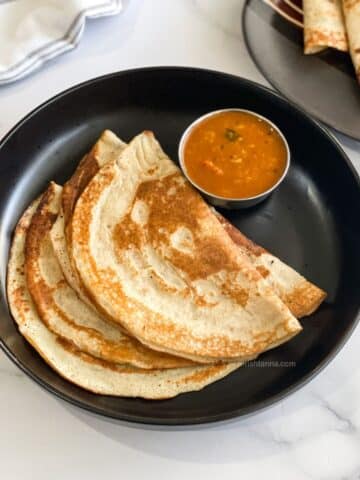 A plate has quinoa dosas with sambar.