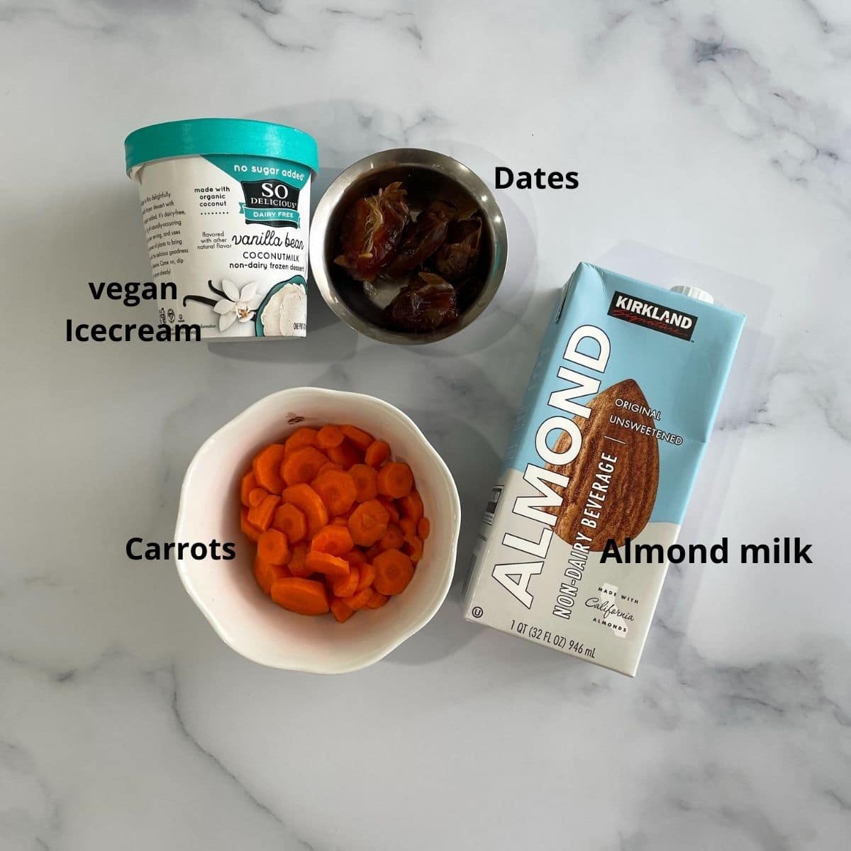A table is with milkshake ingredients like carrots, almond milk and ice cream pint.