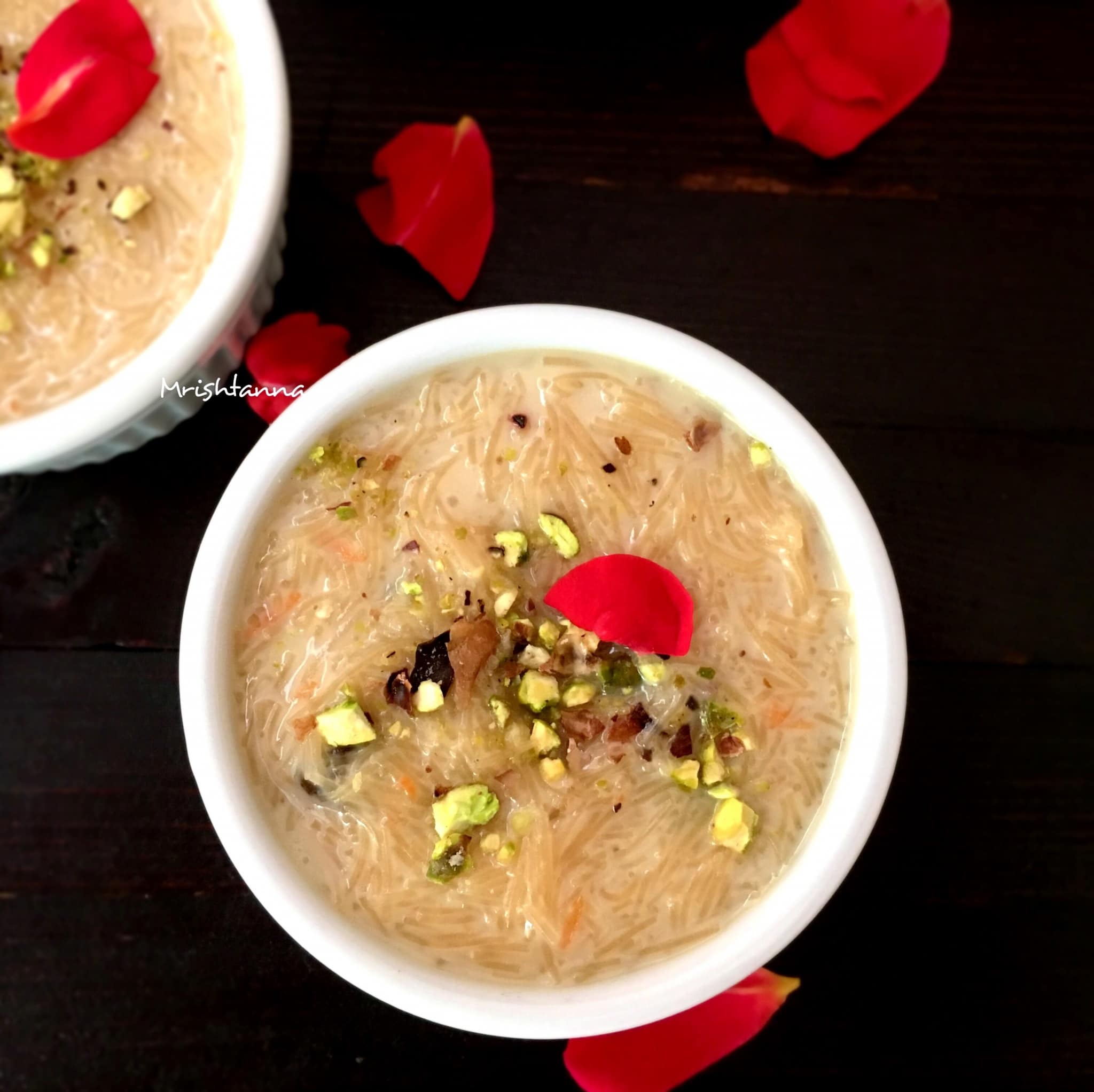 A bowl of sevai kheer and topped with pistachios and rose petals