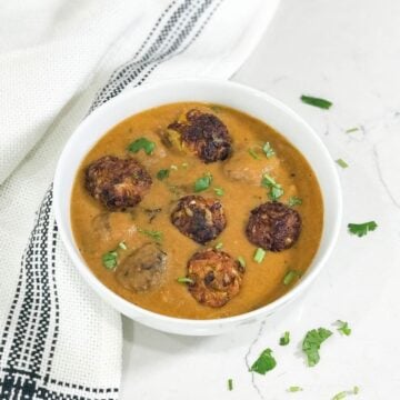 A bowl of curry with cabbage and kofta