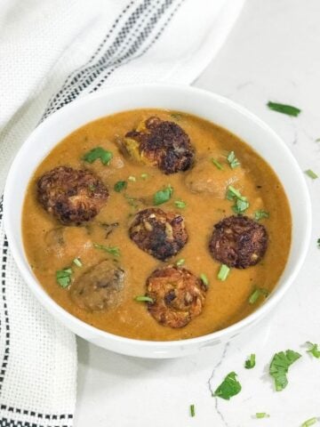 A bowl of curry with cabbage and kofta