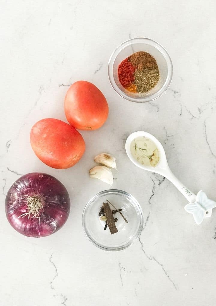 Tomatoes, onion, garlic and whole spices place on the white table