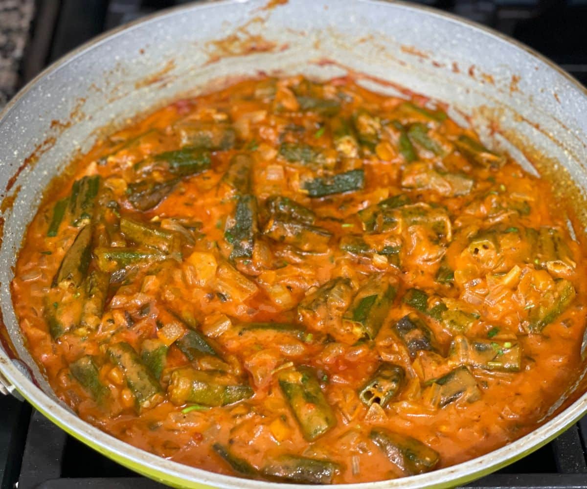 A pan is with bhindi masala over the stove top.