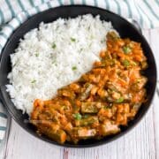 A plate is with bhindi masala and rice on the table with cloth and spoon.