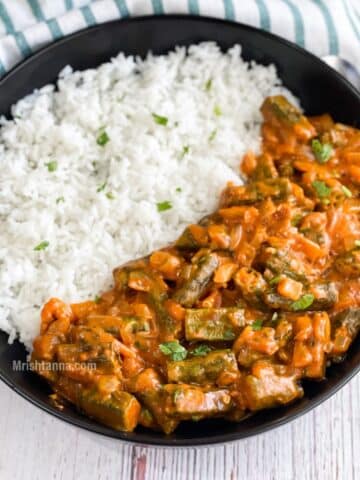 A plate is with bhindi masala and rice on the table with cloth and spoon.