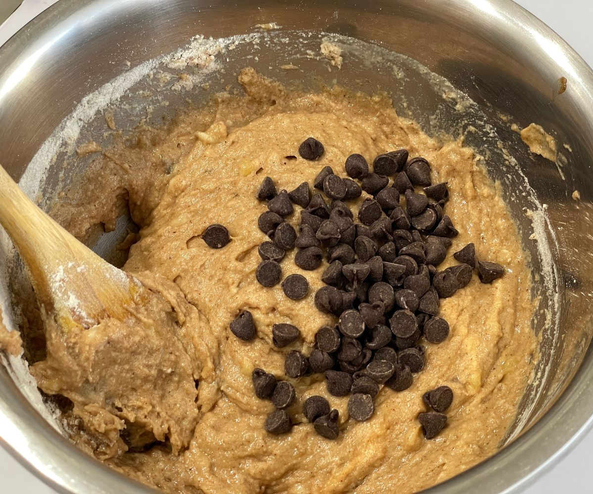 A bowl has almond butter muffin batter and chocolate chips.